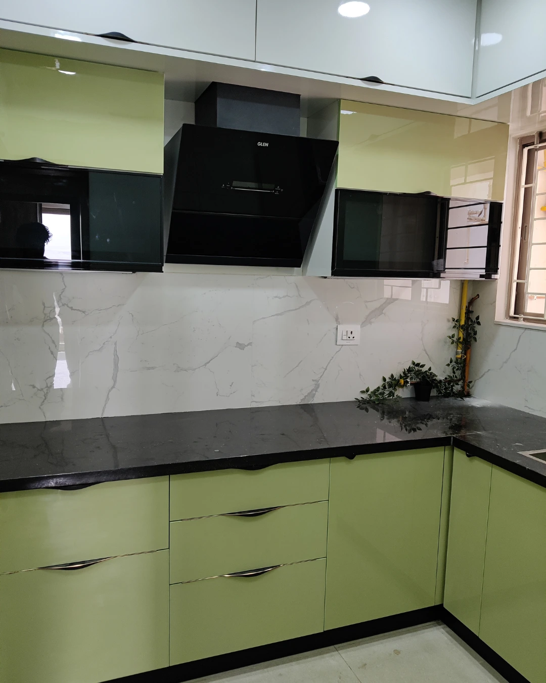 Sage-green kitchen cabinetry with pale backsplash and dark countertop