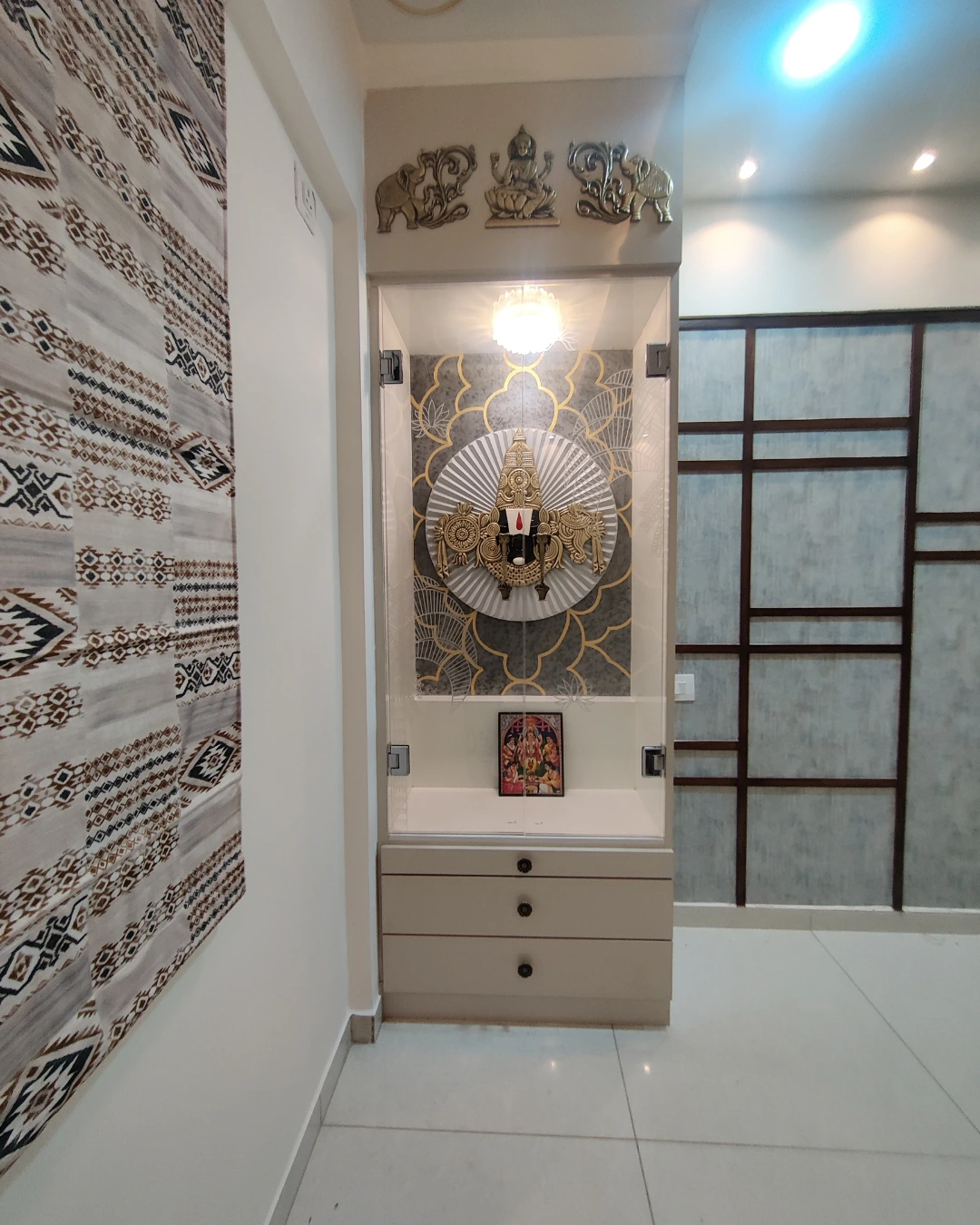 Pooja space with devotional artwork and considered storage