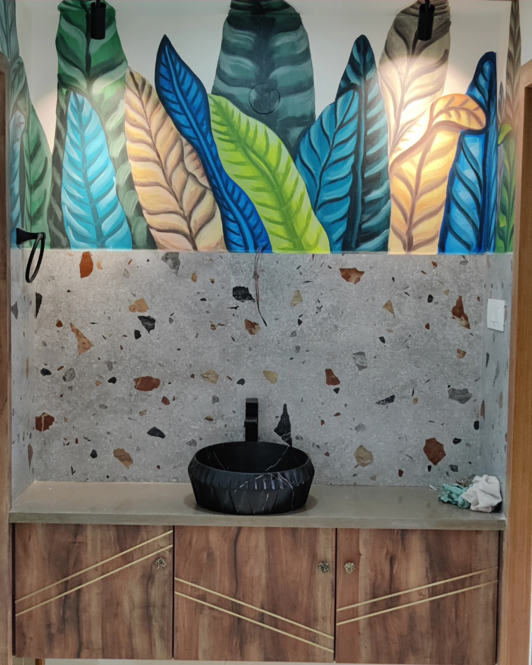 Colourful botanical artwork above a sculptural basin and wood-grain vanity